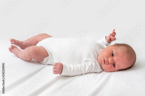 Newborn baby is lying on back on white blanket photo