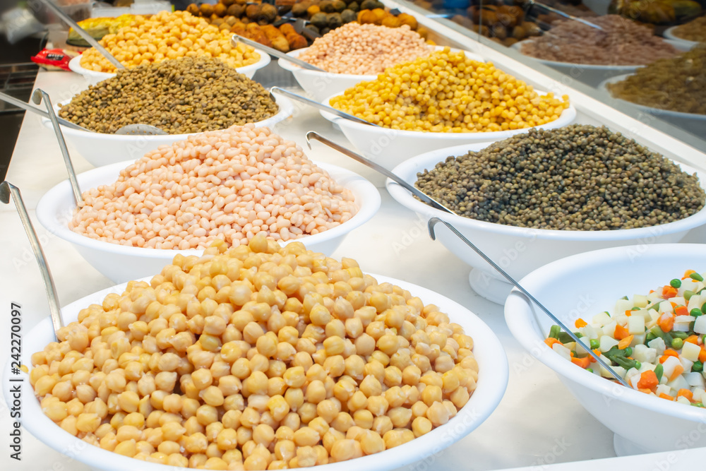 Variety of different types of cooked beans, lentil and peas sold on food market in barcelona in bowls
