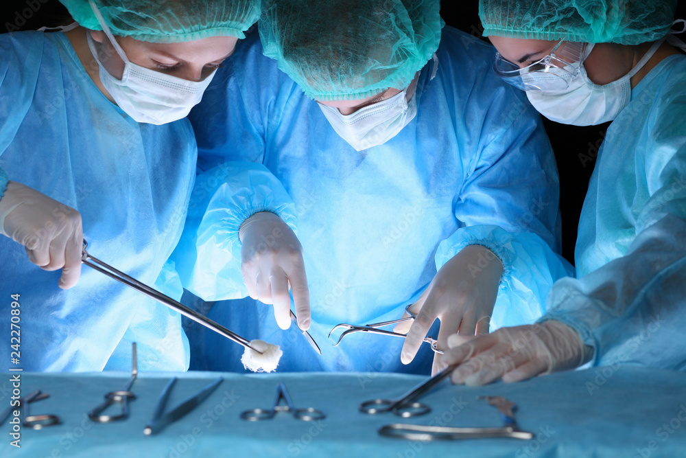 Group of surgeons in masks performing operation. Medicine, surgery and emergency help concepts Group of surgeons in masks performing operation. Medicine, surgery and emergency help concepts