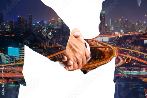 Businessman greeting Shakehand deal with Modern City shining at Night photo