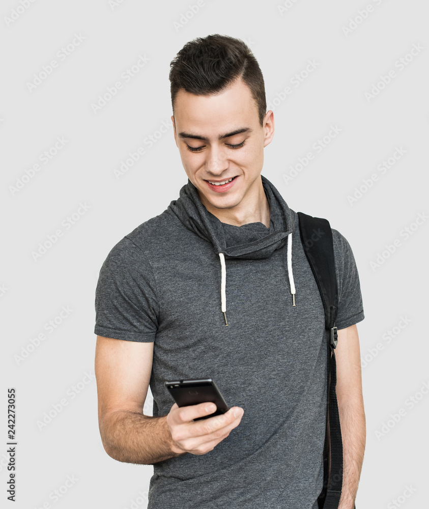 Portrait of young cheerful men with smart phone. Smiling man student texting message. Isolated on gray background Portrait of young cheerful men with smart phone. Smiling man student texting message. Isolated on gray background
