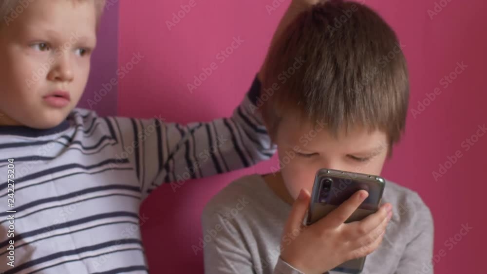 Funny kids lay on sofa to play computer games on smartphone. Parents gave the children a new phone for Christmas. Modern children are well aware of latest technology. Brothers are happy together Funny kids lay on sofa to play computer games on smartphone. Parents gave the children a new phone for Christmas. Modern children are well aware of latest technology. Brothers are happy together