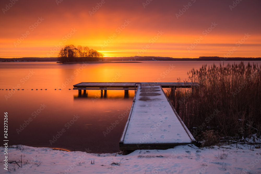 Sunrise over the Swiecajty lake and wooden footbridge near Wegorzewo, Masuria, Poland