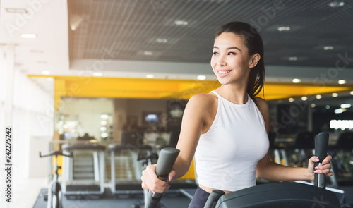 Cuadro en lienzo Woman exercising at elliptical trainer in gym