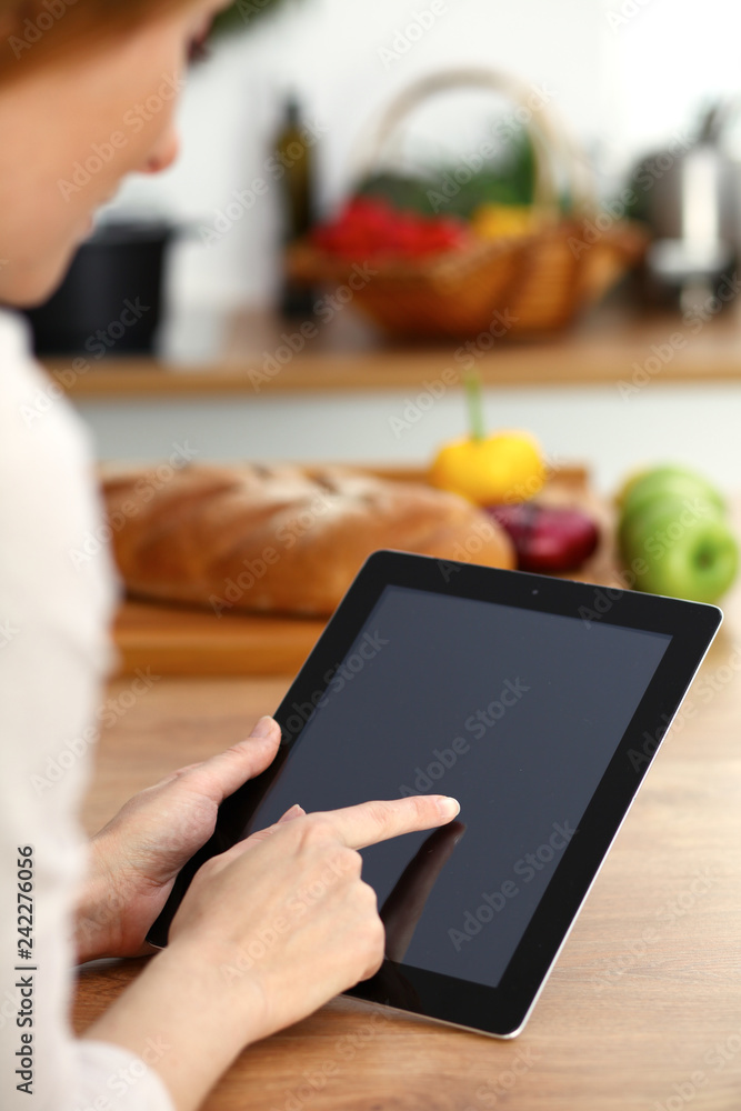 Woman using tablet computer while cooking in kitchen Copy space area at touchpad. Healthy meal, vegetarian food and lifestyle concepts Woman using tablet computer while cooking in kitchen Copy space area at touchpad. Healthy meal, vegetarian food and lifestyle concepts