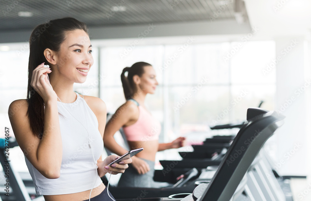 Woman ready to run on treadmill and listening to music