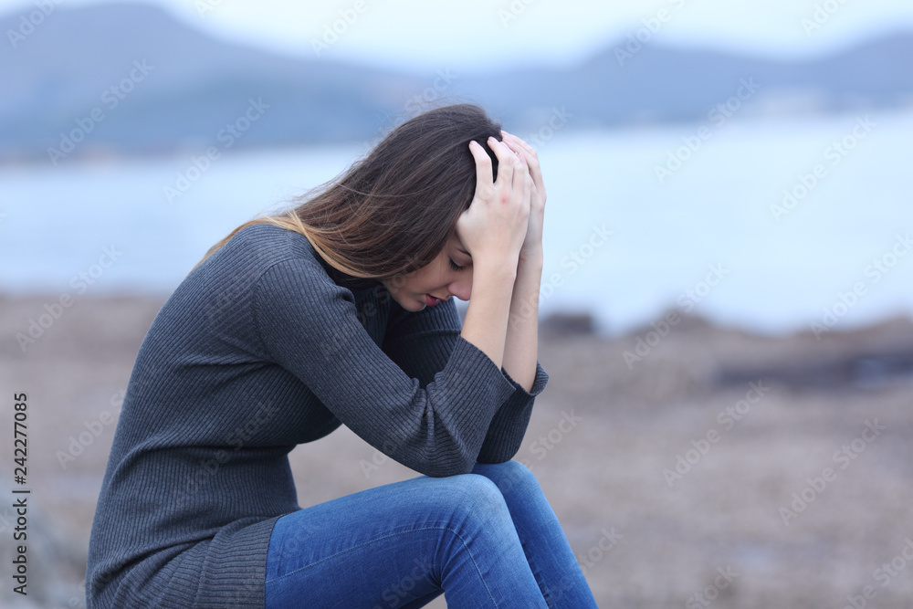 Sad woman complaining sitting on the beach