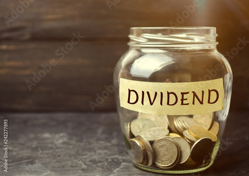 Glass jar with the word Dividend. A dividend is a payment made by a corporation to its shareholders as a distribution of profits. Concept business finance and investment. Saving money. Dividend tax photo