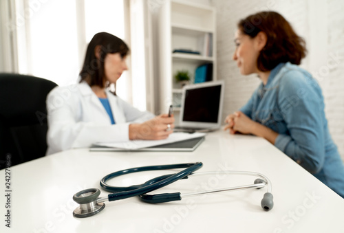 Close-up of stethoscope on table on out of focus background of doctor and patient consultation