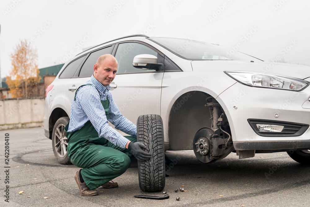 Mechanic with spare wheel and broken car Mechanic with spare wheel and broken car