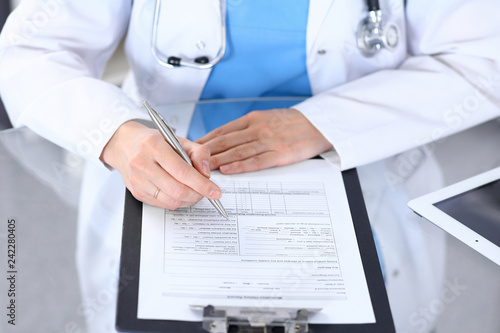 Female doctor filling up medical form on a clipboard  closeup. Healthcare  insurance and medicine concept