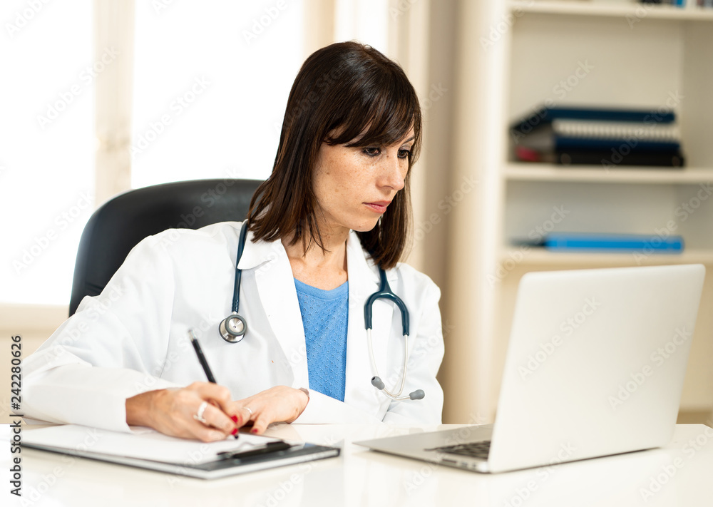 Female doctor working on medical expertise and searching information on laptop at hospital office Female doctor working on medical expertise and searching information on laptop at hospital office