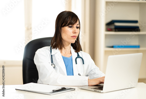 Female doctor working on medical expertise and searching information on laptop at hospital office