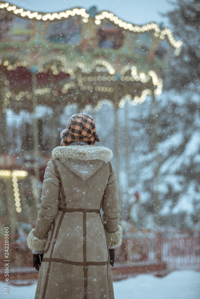 Woman looks at the Victorian carousel on a snowy day Woman looks at the Victorian carousel on a snowy day