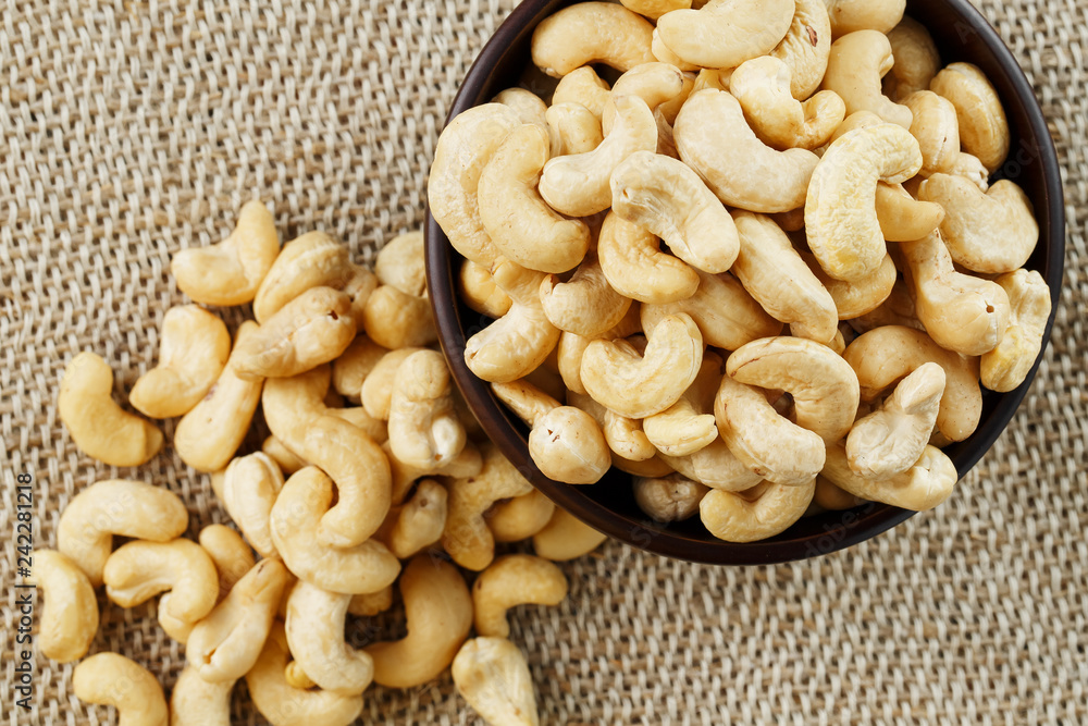 Cashew nuts in a wooden bowl on a burlap cloth background. Cashew nuts in a wooden bowl on a burlap cloth background.