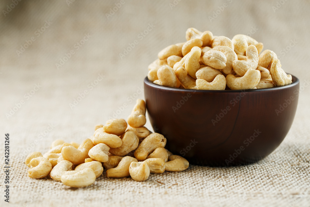 Cashew nuts in a wooden bowl on a burlap cloth background. Cashew nuts in a wooden bowl on a burlap cloth background.