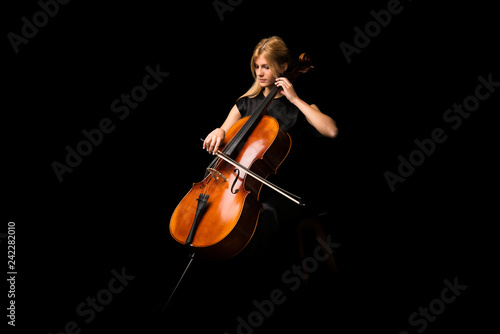 Young girl playing the cello on isolated black background photo