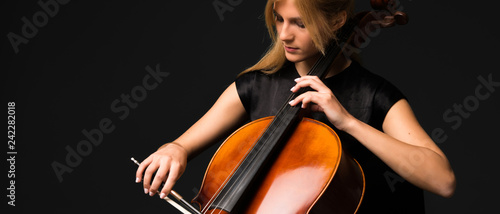 Young girl playing the cello on isolated black background