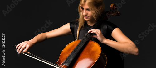 Young girl playing the cello on isolated black background photo