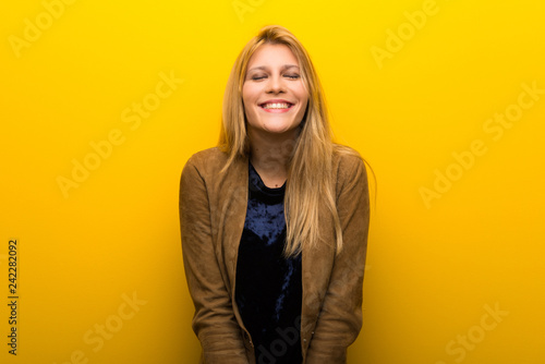 Blonde girl on vibrant yellow background happy and smiling