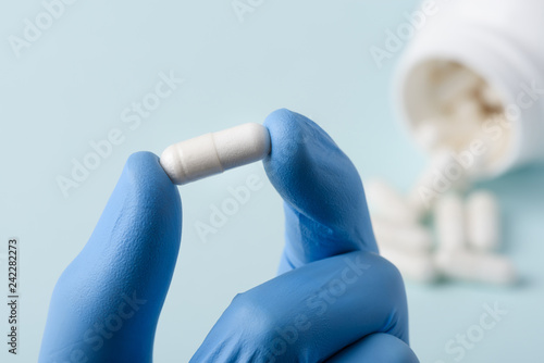Pill in lab scientist hand. Healthcare drug substance analysis concept.