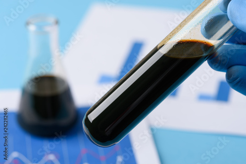 Crude oil in vial test tube in laboratory scientist hand.