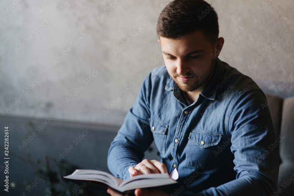 Student read book in cafe. Study and education. Young man spend time in cafe Student read book in cafe. Study and education. Young man spend time in cafe