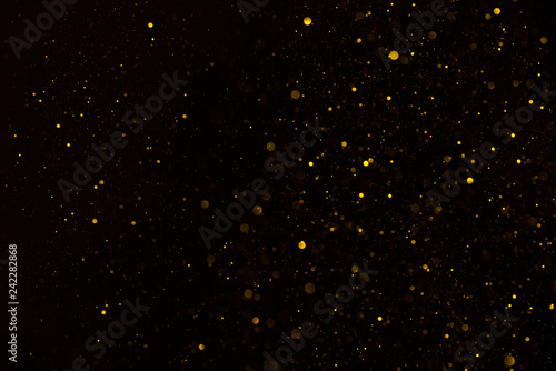 Glitter particles shiny star dust fall on black background