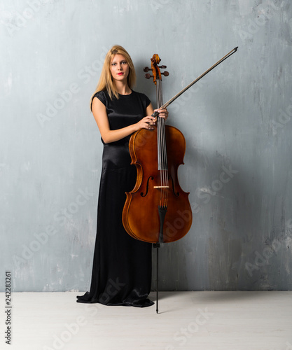 Принти на полотні Young blonde girl with her cello on textured wall background