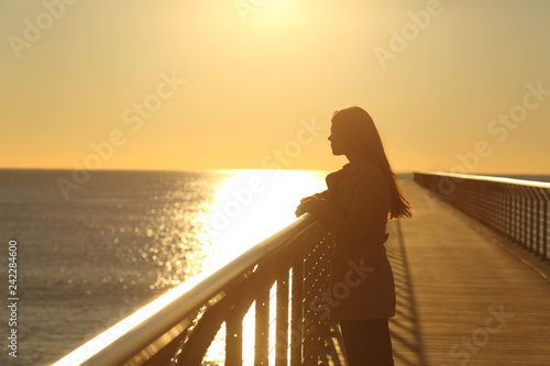 Woman alone contemplating ocean at sunset