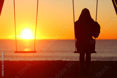 Single woman sitting on a swing contemplating sunset photo