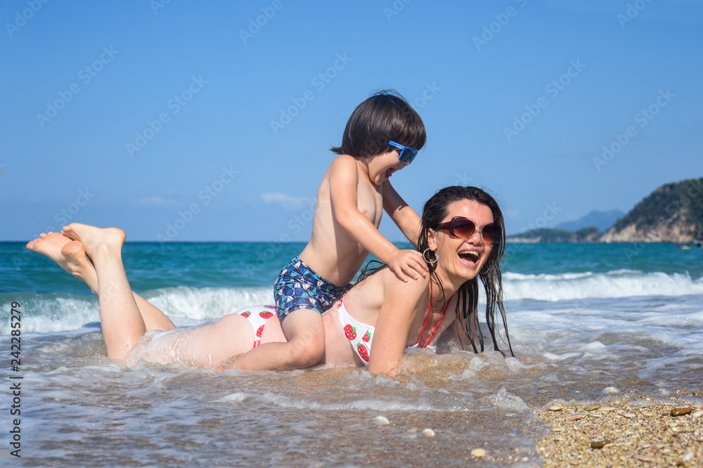Mother and son playing on the beach. Family having fun on beach on travel vacation summer holidays Mother and son playing on the beach. Family having fun on beach on travel vacation summer holidays