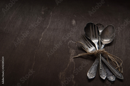Vintage silver spoons, forks and knife on vintage black background. Low-key