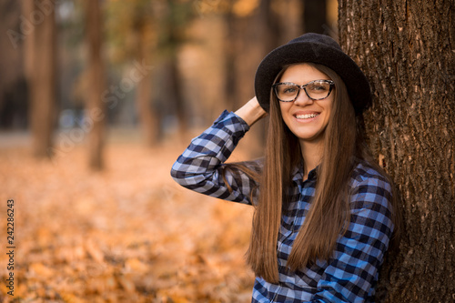 Fashion outdoor portrait of young woman with hat and sunglasses in fall, retro style color tones. Female fashion.