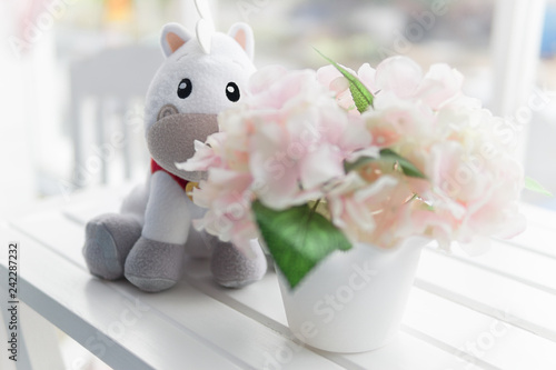 horse doll behind flower bouquet at top of white desk