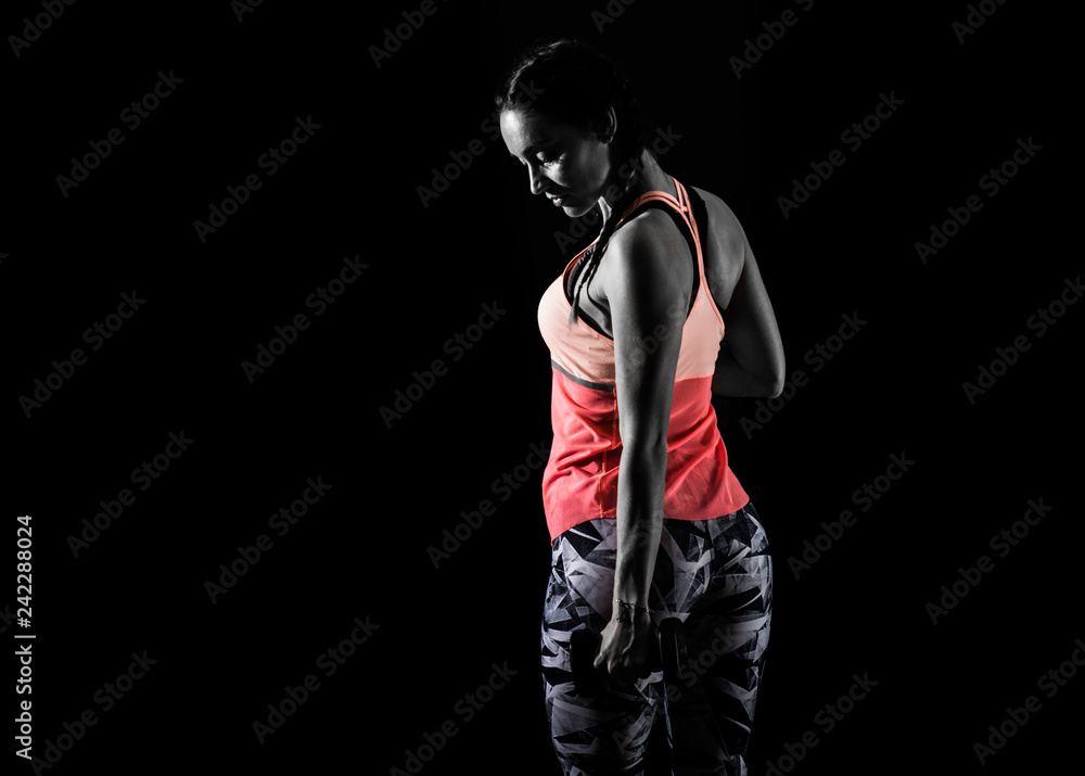 Sport woman on dark background making weightlifting
