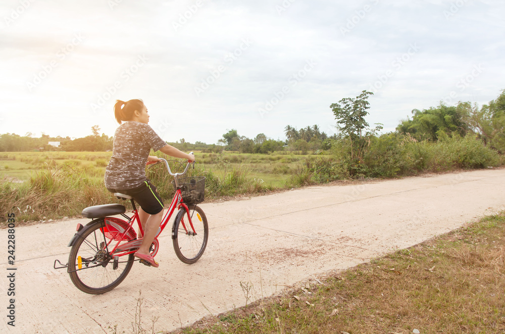 Fototapeta premium Woman riding bicycle relax in a country road.