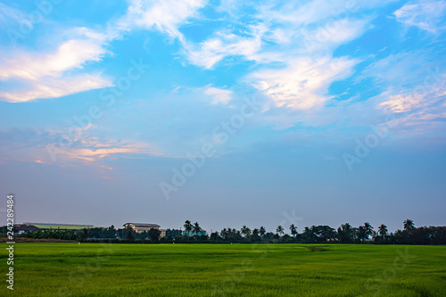 Beautiful light of Sunset with clouds in the sky reflection behind the building and paddy fields.