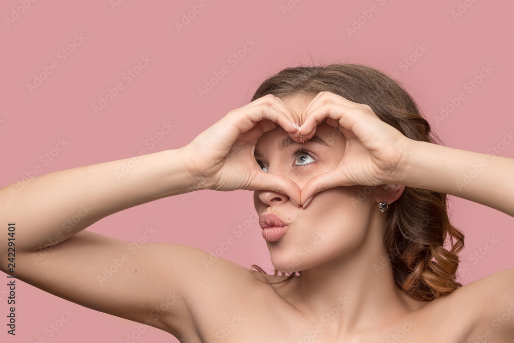 Nice young smiling woman with long wavy silky hair, natural make up looking at camera with hand near chin isolated on pink background. Model with fresh shiny skin and natural make-up. People emotions Nice young smiling woman with long wavy silky hair, natural make up looking at camera with hand near chin isolated on pink background. Model with fresh shiny skin and natural make-up. People emotions