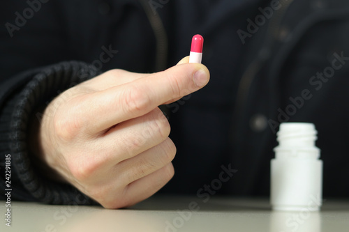 Man takes the antidepressants red and pink capsule photo