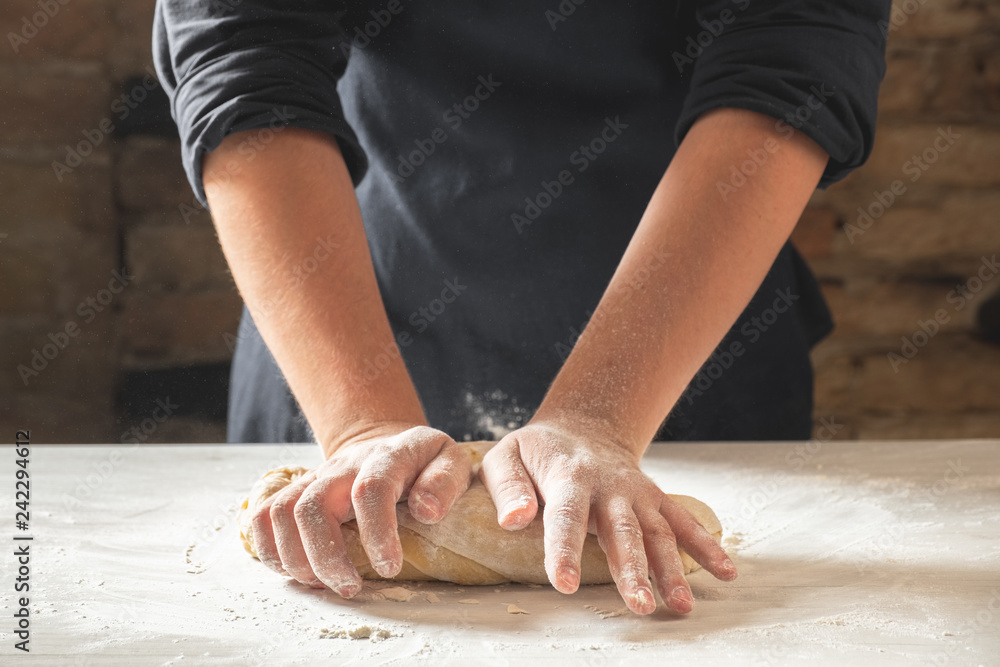 Close view of baker hands kneading dough for traditional bread. Food recipe concept.