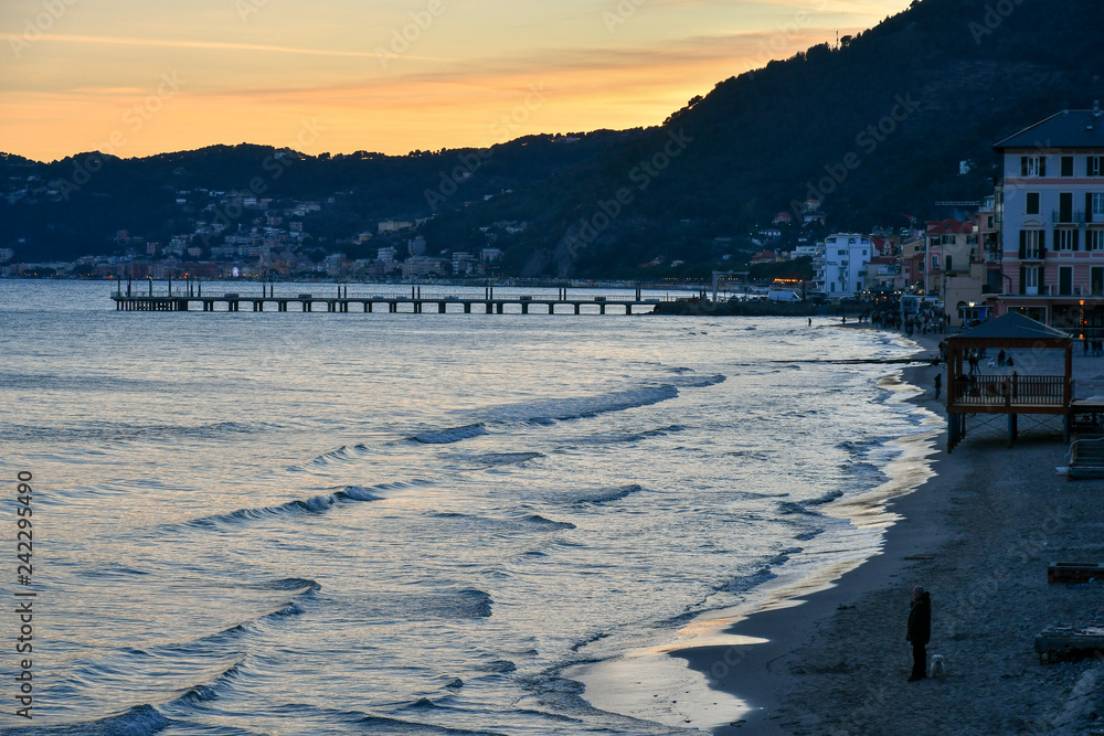 Elevated view of a beach with a pier and tourists at sunset, Alassio, Liguria, Italy