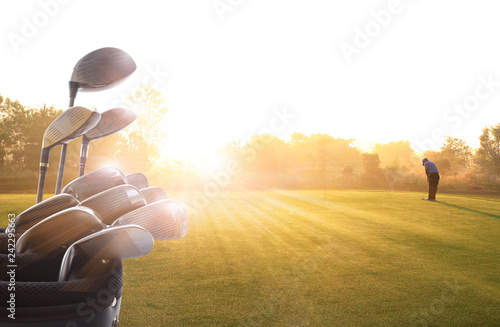 Golf clubs drivers and Golfer putting golf ball on the green over beautiful golf course at the sunset, sunrise time. , morning time