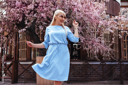 Beautiful model in blue dress by spring blooming tree