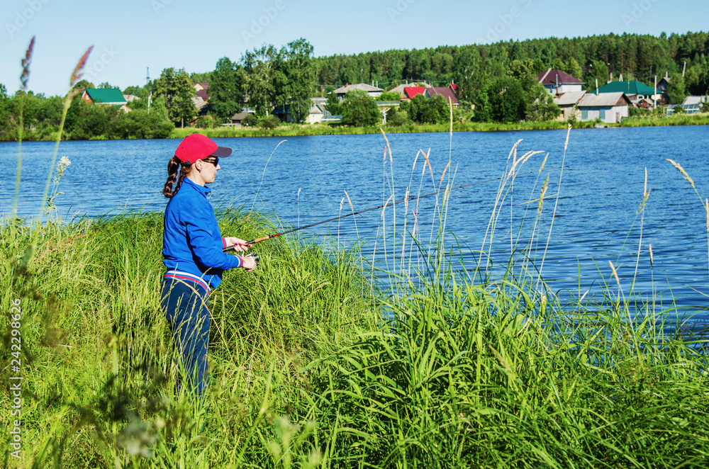 woman with a spinning rod catches a fish in the lake woman with a spinning rod catches a fish in the lake