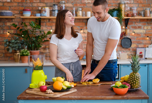 Young couple making smoothie in kitchen