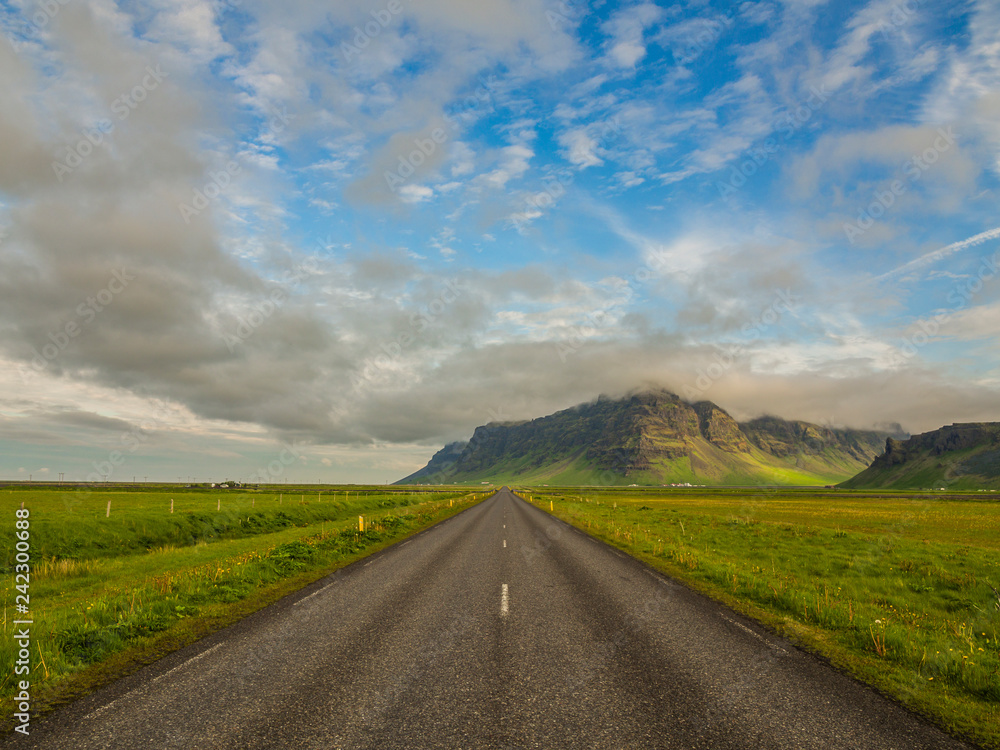 Beautiful icelandic landscape with mountains, green fields and a road.