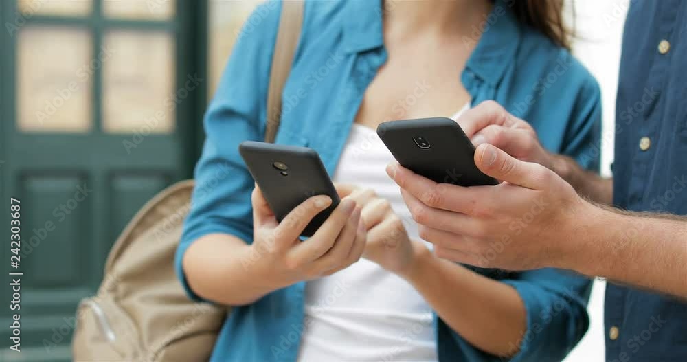 Close up of friend hands sharing smart phones content wireless in the street Close up of friend hands sharing smart phones content wireless in the street