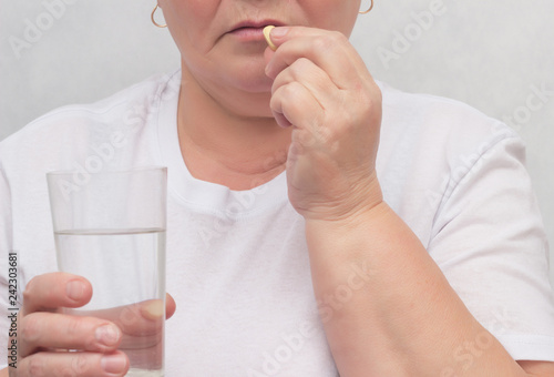 A woman drinks a hormonal pill for treating the thyroid gland, eliminating nodules and normalizing hormones, treatment, close-up photo