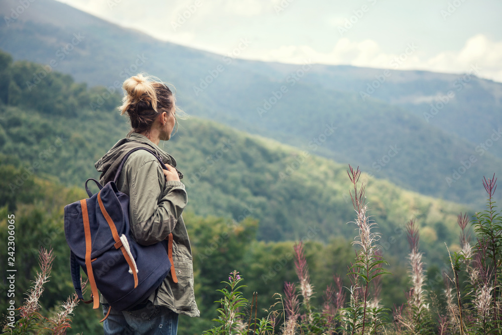 Young woman traveler  with backpack hiking in the mountains,
